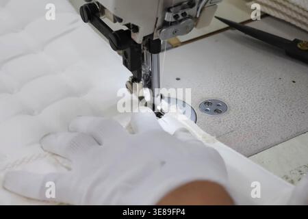 Nähmatratze auf Spezialmaschinen in einer Bekleidungsfabrik, der äußere weiche Teil der Matratze Stockfoto