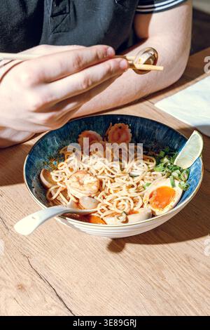 Mann isst Ramen mit Stäbchen. Professionelle Studio-Leuchte Stockfoto