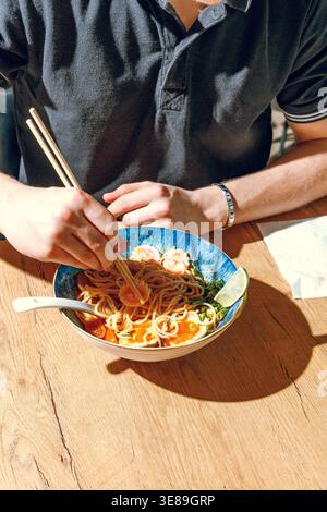 Mann isst Ramen mit Stäbchen. Professionelle Studio-Leuchte Stockfoto