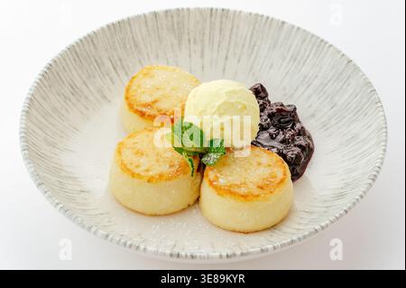 Käsekuchen mit Bananeneis und Kirschmarmelade Stockfoto