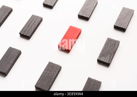 Roter Holzblock, der zwischen schwarzen steht Stockfoto