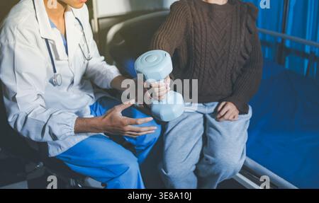 Alte Frauenausbildung bei Physiotherapeutin mit Kurzhanteln zu Hause. Therapeutin, die Seniorin bei Übungen im Pflegeheim unterstützt. Usin bei älteren Patienten Stockfoto