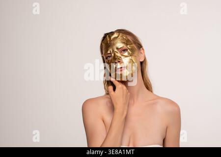 Frau, die goldene Gesichtsmaske für Anti-Aging-Hautpflege und Luxus-Schönheitsroutine im Spa anwendet Stockfoto
