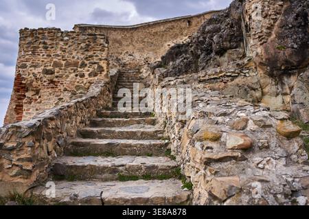 Abgenutzte Steintreppe, die zwischen alten Mauern und natürlichen Felsvorsprüngen in der mittelalterlichen Festung Rupea in Transsilvanien, Rumänien, hinaufsteigt Stockfoto