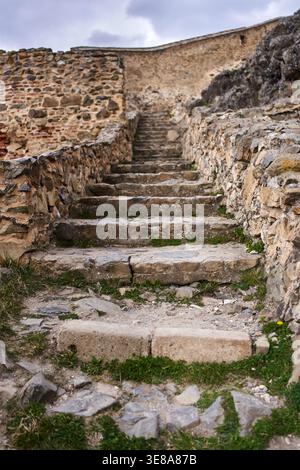Abgenutzte Steintreppe, die zwischen alten Mauern und natürlichen Felsvorsprüngen in der mittelalterlichen Festung Rupea in Transsilvanien, Rumänien, hinaufsteigt Stockfoto