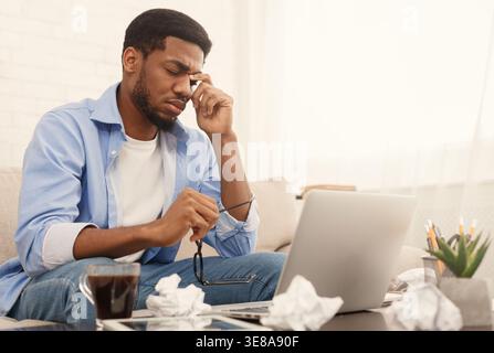 Erschöpft afroamerikaner an seinem Arbeitsplatz zu Hause, Stockfoto