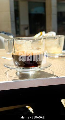 Nahaufnahme von zwei Glas Espresso-Kaffeetassen auf einem Holztisch in einem Café im Freien in der Sonne algarve portugal Stockfoto