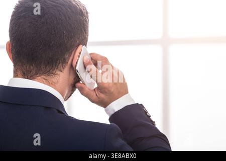 Geschäftsmann im Anzug, der auf dem Handy spricht, Rückansicht Stockfoto