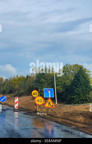 Straßenschilder, die den Fahrer auf Bauarbeiten, einen bevorstehenden Umweg und eine Geschwindigkeitsbegrenzung von 40 km/h hinweisen Stockfoto