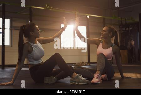Zwei Freunde sitzen nach dem Workout auf dem Boden des Fitnessstudios Stockfoto