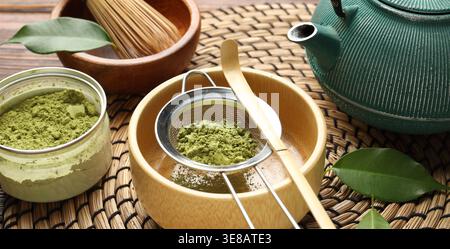 Matcha-Pulver in Schüssel und Teekanne auf dem Tisch, Nahaufnahme Stockfoto