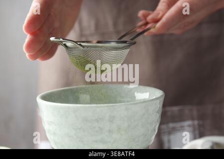 Frau, die Matcha-Pulver in eine Schüssel siebt, Nahaufnahme Stockfoto