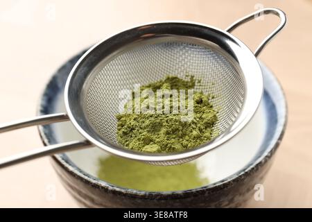 Matcha-Pulver in eine Schüssel am Holztisch, Nahaufnahme Stockfoto