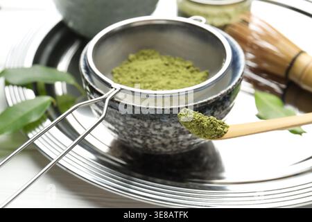 Matcha-Pulver in Schüssel auf weißem Holztisch sieben, Großaufnahme Stockfoto