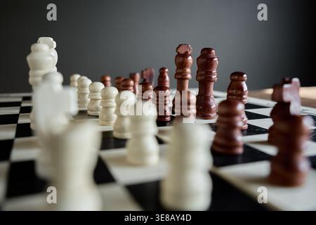 Weiße und braune Schachfiguren auf Schachbrett mit gegenüberliegenden Seiten. Konzept von Konfrontation, Balance, Positionsspiel und Wettbewerbsspannung. Stockfoto