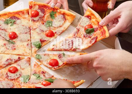 Hände, die Scheiben von italienischer Pizza nehmen, Nahaufnahme Stockfoto