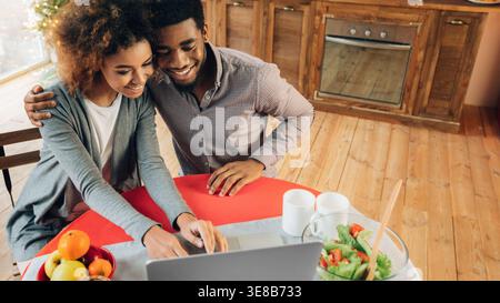 Happy afrikanisch-amerikanisches Paar mit Laptop in der Küche Stockfoto