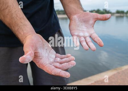 Athlet zeigt strukturierte Hände mit Kreide und Callus nach Outdoor-Calisthenics-Workout Stockfoto