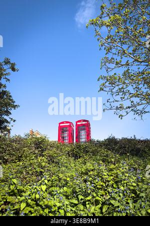 8. April 2026 - London, Großbritannien - zwei traditionelle britische Rote Telefonboxen an einem sonnigen blauen Himmel Stockfoto
