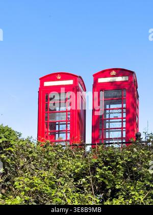 8. April 2026 - London, Großbritannien - zwei traditionelle britische Rote Telefonboxen an einem sonnigen blauen Himmel Stockfoto