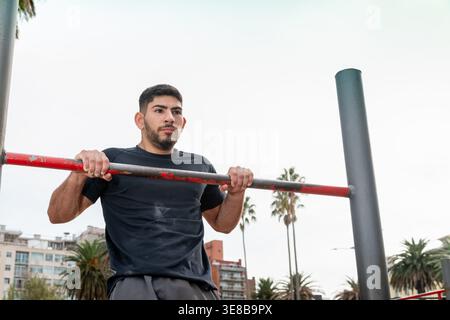 Ein Mann, der Calisthenics macht, zieht draußen an und konzentriert sich auf Krafttraining Stockfoto