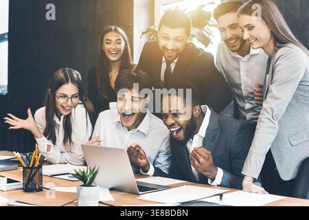 Glückliche Geschäftsleute feiern Erfolg mit Blick auf ein Notebook Stockfoto
