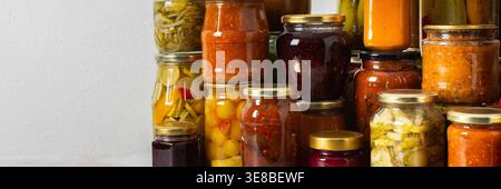 Canning ist eine häufige Aktivität in der Küche, da die Theke mit Gemüse und Obst gefüllte Gläser säumen. Diese Praxis hilft dabei, Lebensmittel für den Gewinn zu bewahren Stockfoto