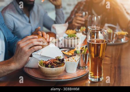 Freunde essen Burger und genießen Bier in der Bar Stockfoto