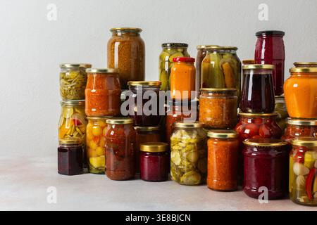 Canning ist eine häufige Aktivität in der Küche, da die Theke mit Gemüse und Obst gefüllte Gläser säumen. Diese Praxis hilft dabei, Lebensmittel für den Gewinn zu bewahren Stockfoto