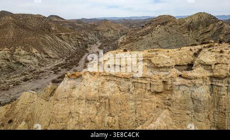 Ein spektakulärer Blick aus der Luft fängt die wilde Essenz der Tabernas-Wüste ein. Steile Badlands und ein trockenes Flussbett, bekannt als rambla, winden sich durch die Stratif Stockfoto
