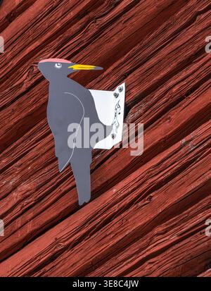 Metallvogel-Silhouette, montiert auf verwittertem rotem Holzblech, dekorative Wandbefestigung mit Schraubverschlüssen Stockfoto