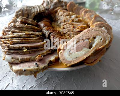Ein Teller mit Aufschnitt wird für die Gäste bei einer Zusammenkunft am Nachmittag arrangiert. Verschiedene Fleischgerichte werden in Scheiben geschnitten und auf einem weißen Teller serviert. Stockfoto