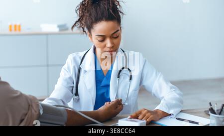 Der Arzt überprüft den Blutdruck des Patienten während der routinemäßigen Gesundheitsberatung in der Klinik Stockfoto