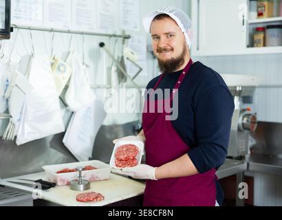 Kochen von Halbfertigprodukten – man zeigt Fleischkoteletts mit speziellen Geräten Stockfoto