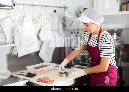 Kochen halbfertiger Produkte - Mädchen bereitet Fleischkoteletts mit speziellen Geräten zu Stockfoto