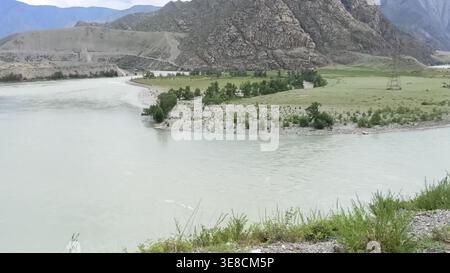 Blick von der Spitze der Kurve eines breiten Bettes auf einen wunderschönen Fluss umgeben von hohen Bergen an einem bewölkten Sommertag. Fluss Katun, Altai, Sibirien, Rus Stockfoto