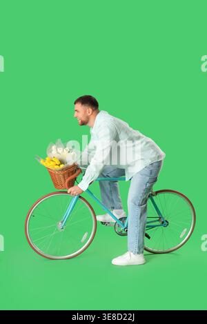 Liefermann mit Blumen, der Fahrrad auf grünem Hintergrund fährt Stockfoto