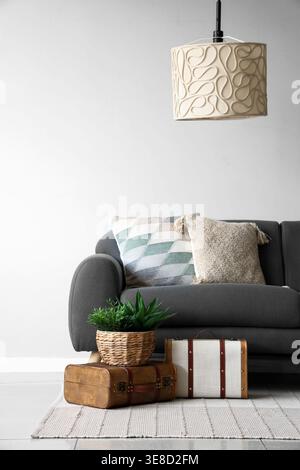 Graues Sofa mit weichen Kissen in der Nähe der weißen Wand Stockfoto