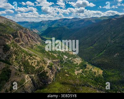 Hochwinkelantenne der Alpine Loop Backcountry Road, die sich durch ein üppiges Tal in Colorado schlängelt. Schroffe Gipfel und Sommerwolken in den Rocky Mountains. Stockfoto