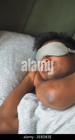 Mann, der mit Augenmaske auf einem Bett schläft Stockfoto
