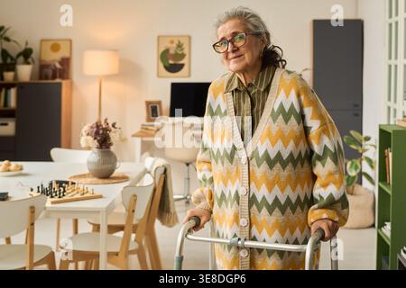 Porträt einer älteren kaukasischen Frau, die zu Hause Walker benutzt, zeigt Mobilitätsunterstützung, Altern, Rehabilitation, unabhängiges Leben. Nützlich für Gesundheitswesen, Seniorenpflege, Versicherungsmarketing Stockfoto