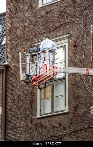 Professioneller Mitarbeiter An Aufzugsplattformen, Reinigungsfenster Von Ziegelgebäuden, Wartungsservice In Der Höhe Stockfoto