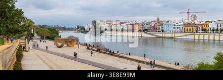 Sevilla, Spanien - 12. Februar 2020: Weitläufiger Panoramablick auf die Fußgängerpromenade entlang des Guadalquivir-Flusses mit entspannenden, modernen Skulpturen Stockfoto