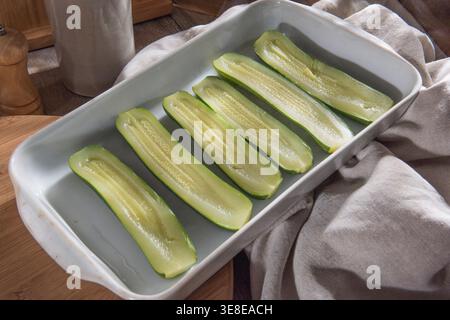 Zucchini-Hälften in einer Auflaufform vorbereitet, bereit für das Kochen einer gesunden vegetarischen Mahlzeit Stockfoto