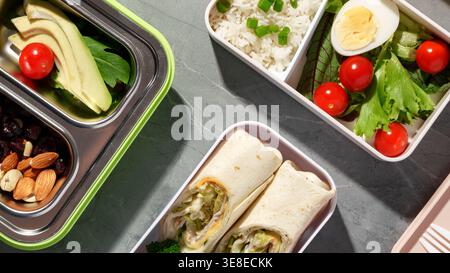 Gesunde Lunchboxen mit Gemüse, Reis und Wraps auf einer grauen Oberfläche Stockfoto