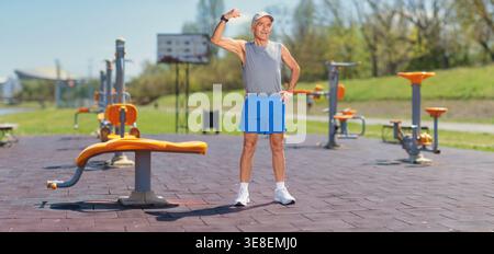 Ein älterer Mann zeigt Armmuskeln in einem Fitnessraum Stockfoto