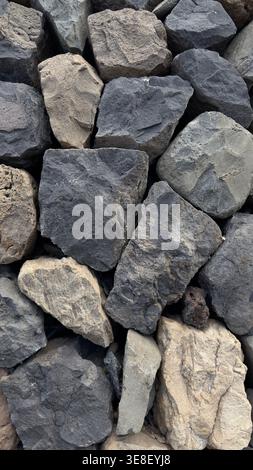 Nahaufnahme einer vulkanischen Steinmauer aus natürlichem Basaltgestein an der Küste von Teneriffa, Kanarischen Inseln. Grobe Textur unregelmäßiger Steine, die in angeordnet sind Stockfoto
