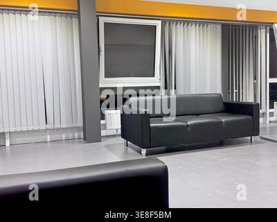 Minimalistischer Büroinnenraum mit Lederstuhl in Grautönen Stockfoto