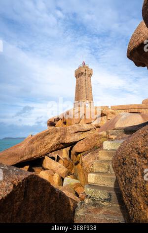 Der Leuchtturm Mean Ruz erhebt sich über seiner Granitbrücke in Tregastel, an der Pink Granite Coast in der Bretagne, Frankreich, mit Blick auf raue See und abgerundete Kanten Stockfoto