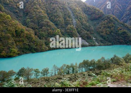 Türkisfarbener See, umgeben von bewaldeten Berghängen in herbstlicher landschaftlicher Landschaft Stockfoto